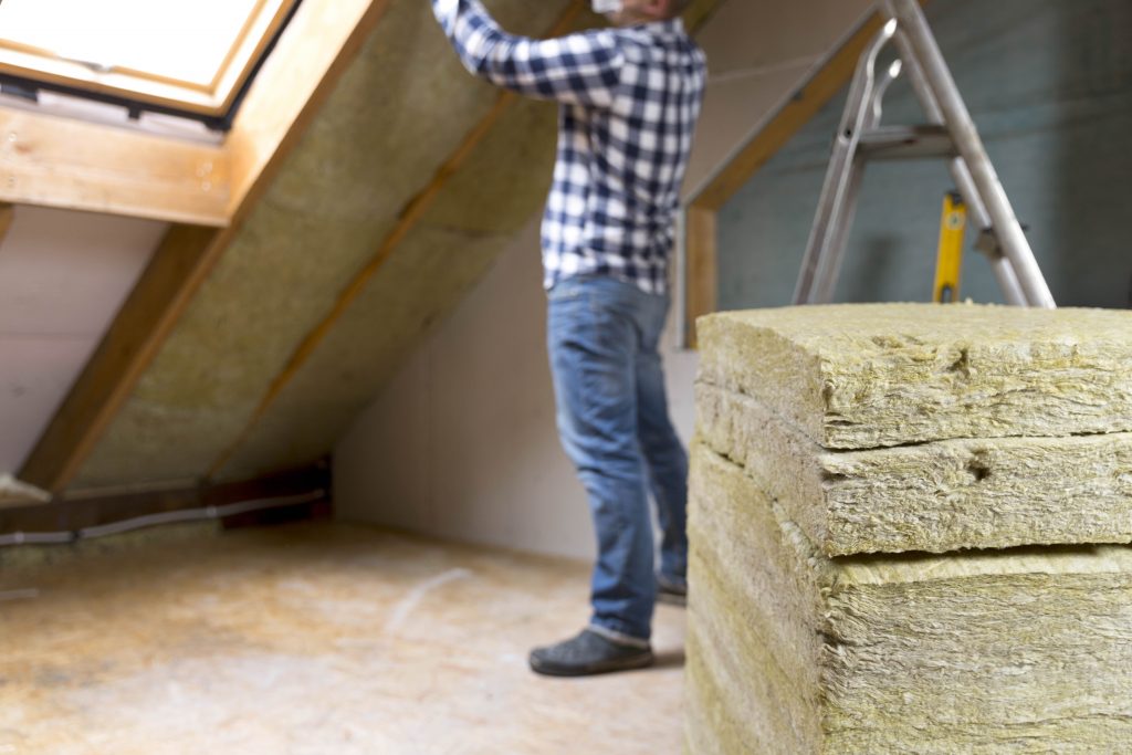 Insulation Rests Man installing thermal roof insulation layer – using mineral wool ...